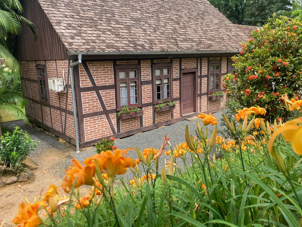 Fachada enxaimel com jardim de lírios laranja